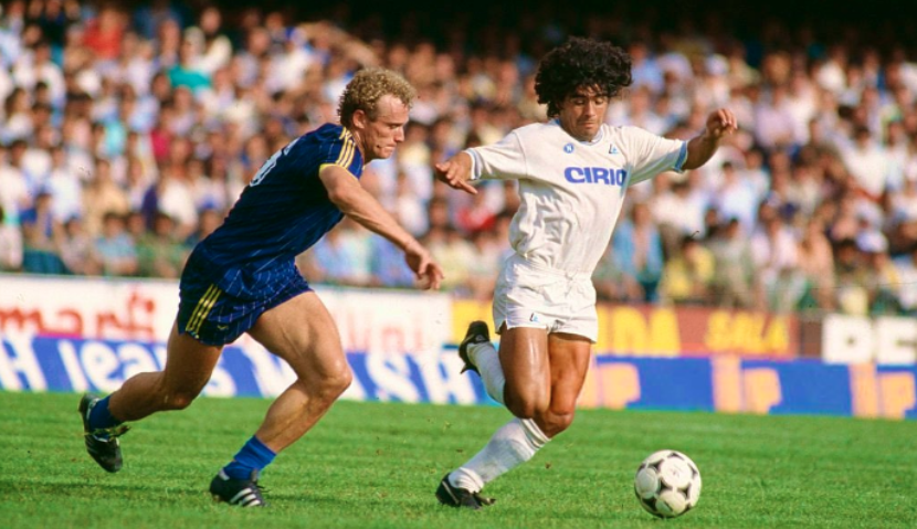 Hans Peter Briegel contende il pallone a Diego Armando Maradona all'esordio in Serie A durante Verona - Napoli allo stadio Bentegodi di Verona, 16 settembre 1984