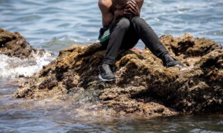 Spanish city of Ceuta in crisis with influx migrants epa09209429 A migrants sits on a rock after crossing the border of Tarajal in Ceuta, Spain, 18 May 2021. On the night of 17 May, a total of 5,000 Moroccan nationals entered into the Spanish city of Ceuta, loacted in the North African coast, by sea side and hundreds of migrants continue to attempt doing so. The Spanish authorities have deployed the army to patrol on the border separating Ceuta in the Spanish side from the Moroccan side, in a bid to control this latest surge of entry attempts. EPA/BRAIS LORENZO