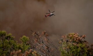 Palisades Fire prompts evacuations in Topanga, California epaselect epa09203442 A helicopter flies over the Palisades Fire burning towards a hiking trail in Topanga, California, USA, 15 May 2021. The fire had burned over 700 acres by nightfall, prompting evacuations. EPA/Christian Monterrosa